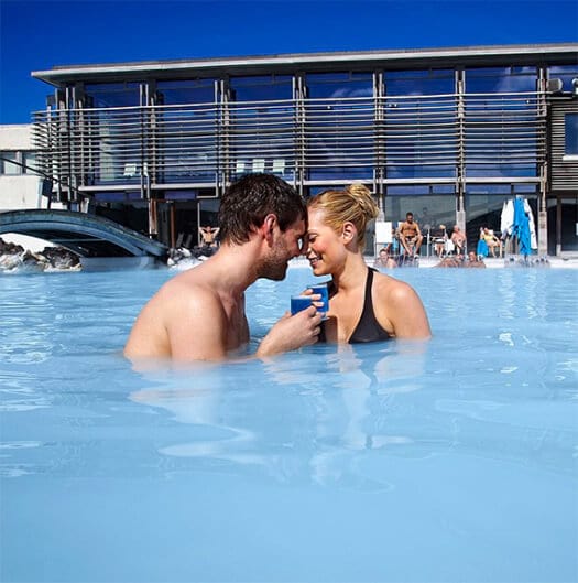 Man and woman seen from the chest up in blue water