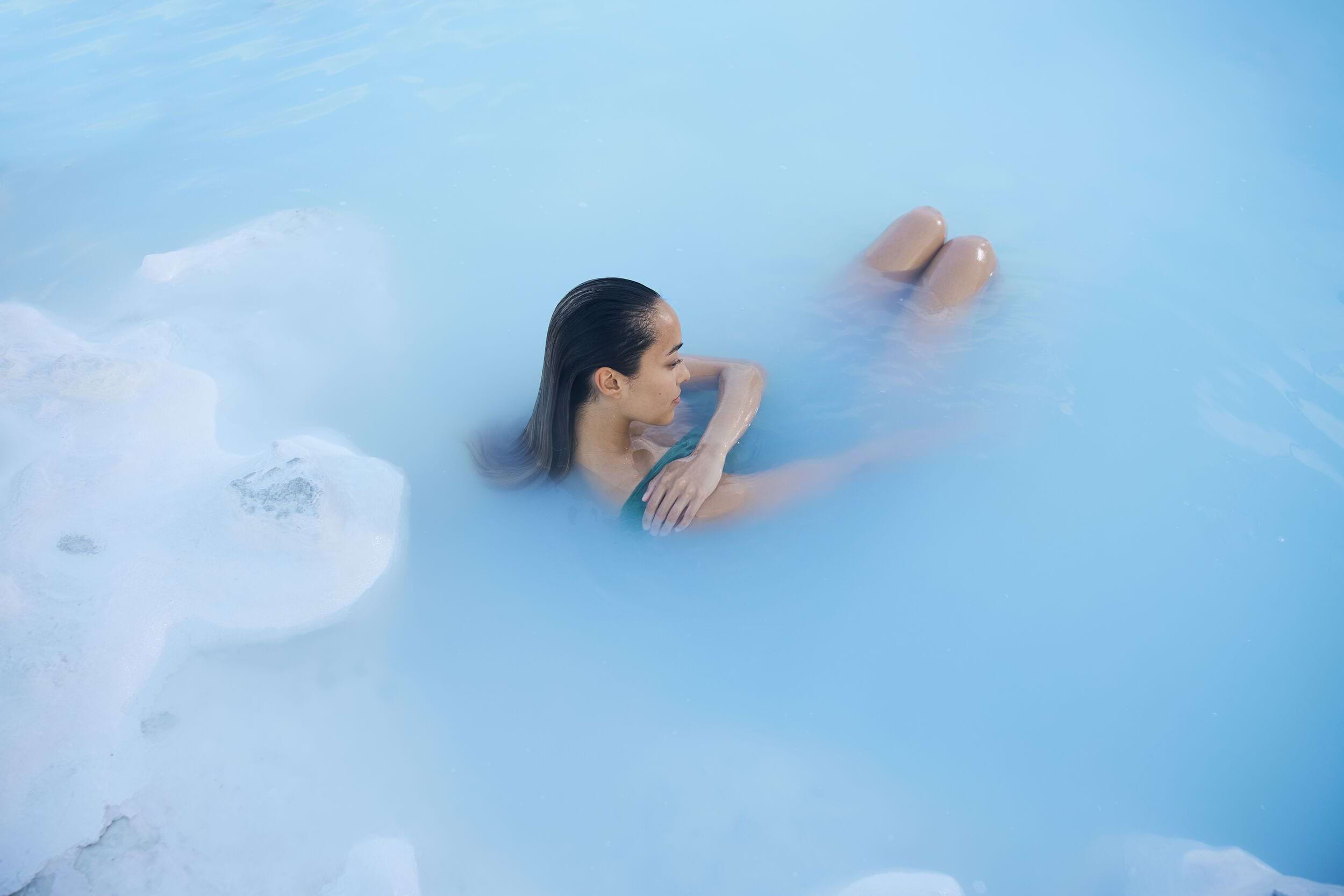 A woman relaxing in the milky blue waters of the Blue Lagoon
